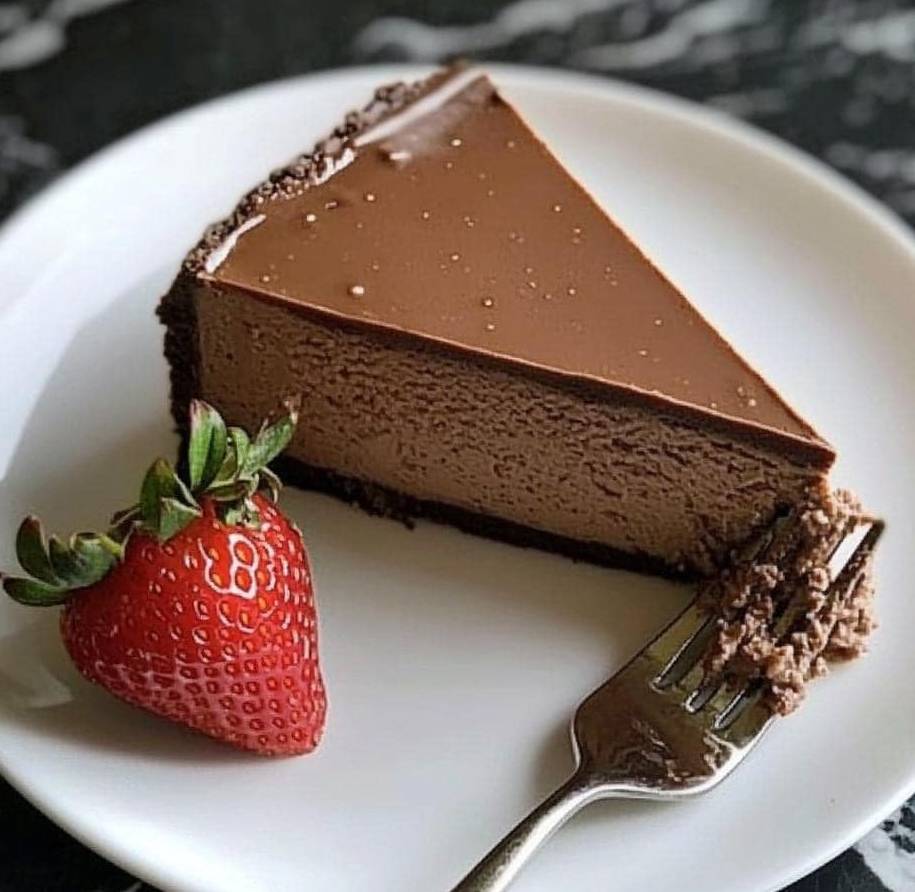 Part de cheesecake au chocolat avec une base croustillante de biscuits et une garniture au chocolat noir.