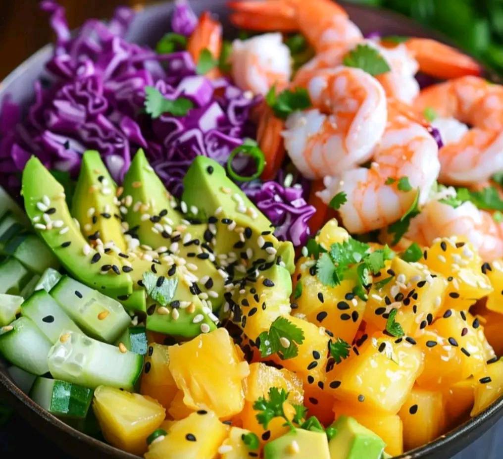 Salade hawaïenne colorée avec crevettes, ananas, avocat et chou rouge, servie dans un bol avec une garniture de graines de sésame et coriandre.