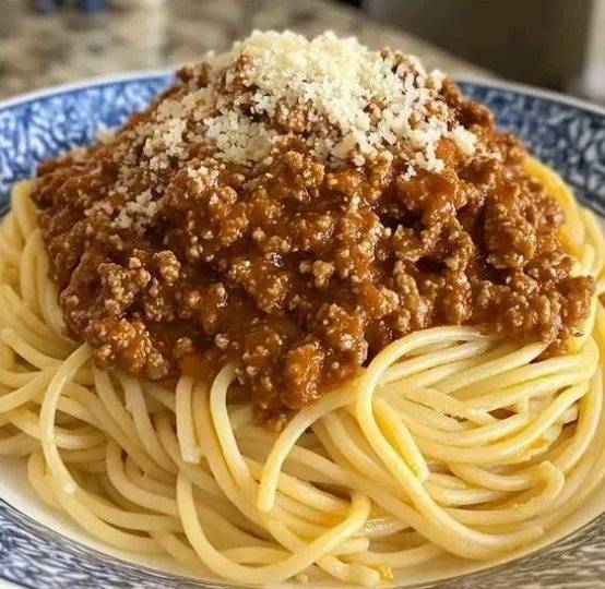  Assiette de spaghetti bolognese garnie de parmesan râpé et de feuilles de basilic frais.