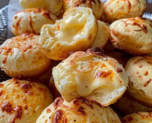 Pancitos de queso dorados y esponjosos, servidos en una tabla de madera con queso rallado por encima.