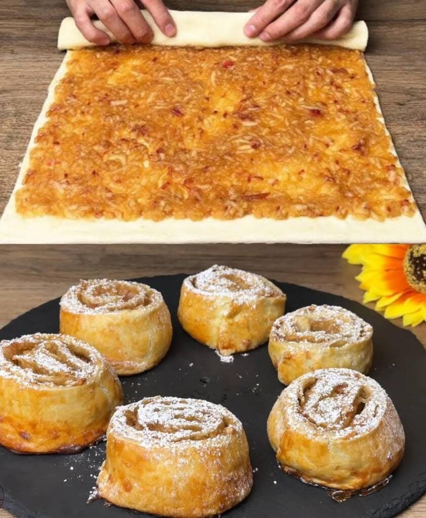 Roulés feuilletés aux pommes dorés, saupoudrés de sucre glace, servis sur une assiette en bois.