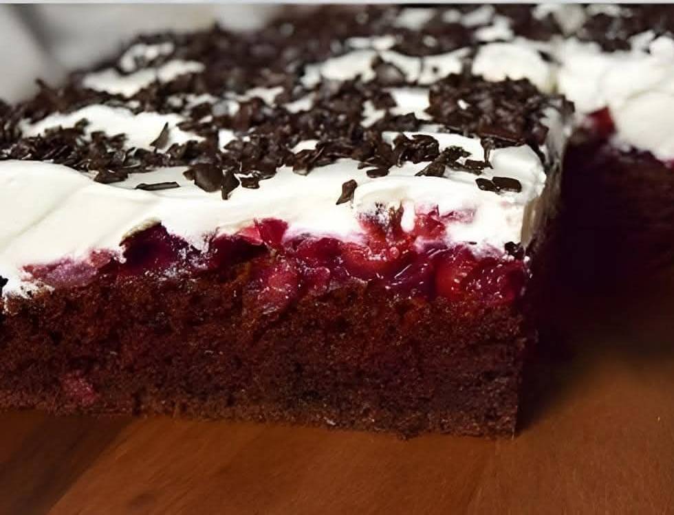 Gâteau Forêt Noire en plaque, garni de chantilly, cerises et copeaux de chocolat, servi sur un plateau.