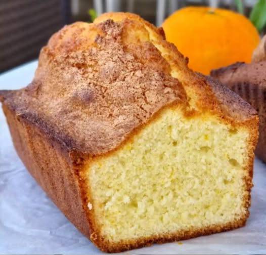 Cake doré à l’orange, nappé de sirop, avec une tranche coupée montrant sa texture moelleuse.