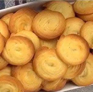 Biscuits sablés viennois dorés, en forme de spirale et trempés dans du chocolat noir, disposés sur une assiette élégante.