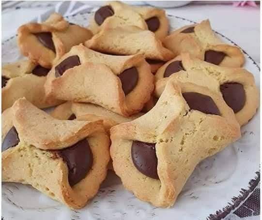  Biscuits fourrés au chocolat dorés, disposés sur une assiette, avec une tasse de café.