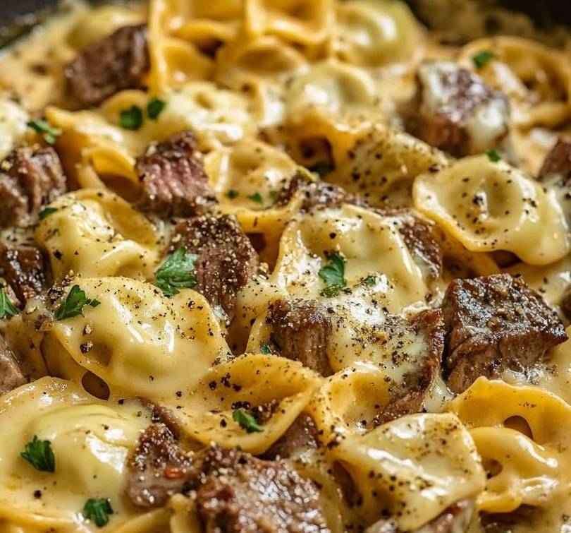  Assiette de tortellinis en sauce crémeuse avec steak de bœuf et fromage fondu, garnie de persil frais