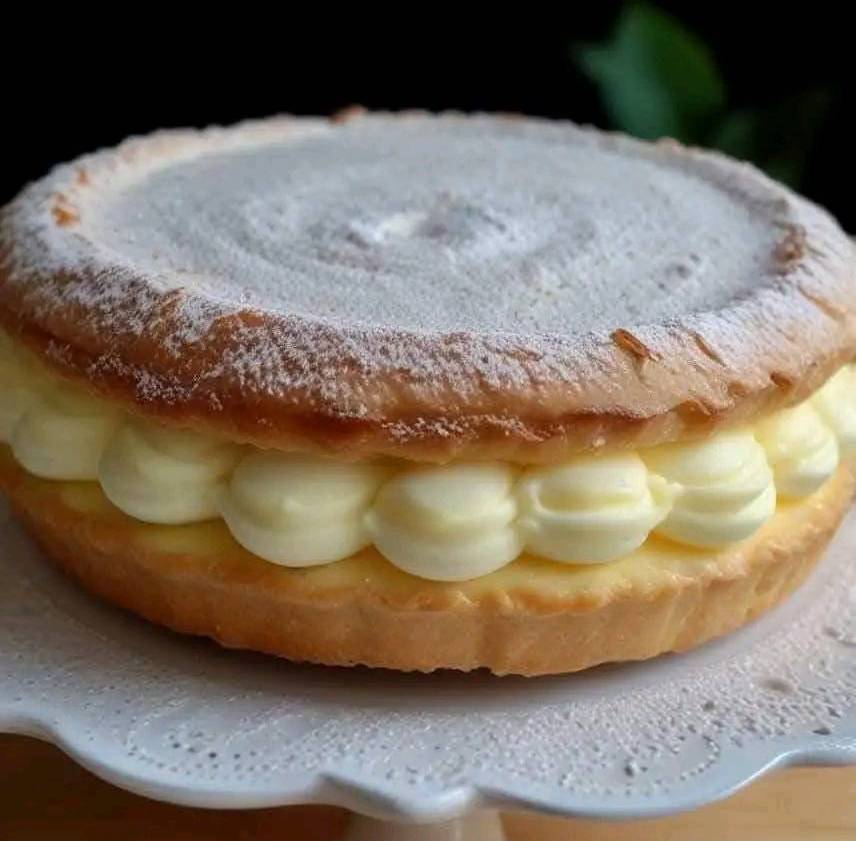 Tarte Tropézienne dorée et moelleuse, saupoudrée de sucre perlé et garnie d’une crème onctueuse à la vanille